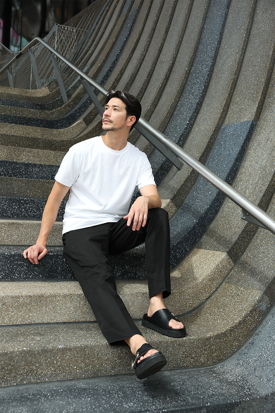 白いTシャツを黒いパンツと合わせた街中での着用スタイル